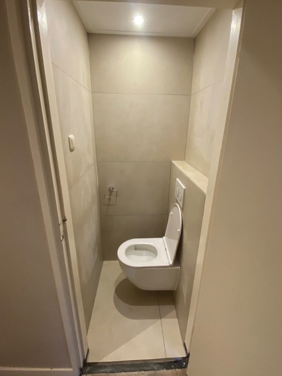 Betegelde toiletruimte met wandtoilet